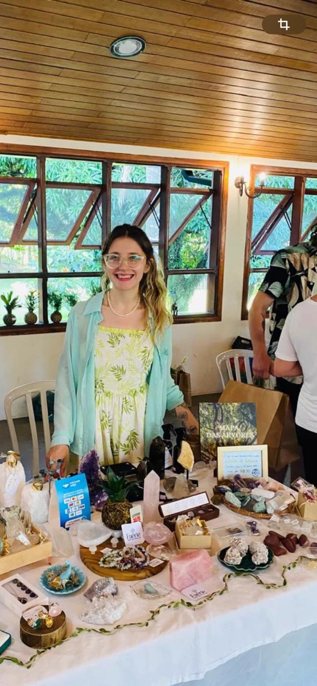 Mesa da Faërie numa feira, com cristais e o livro Mapa das Árvores